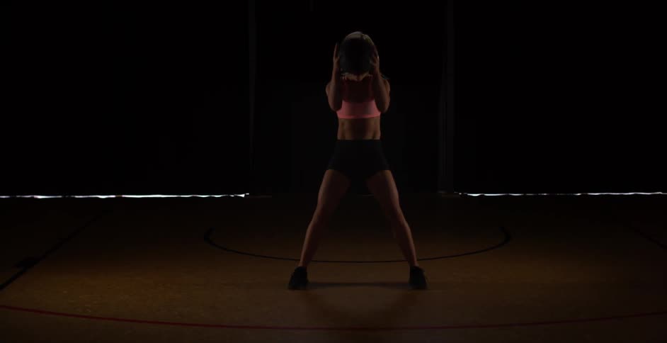 Woman swings a medicine ball down and back up