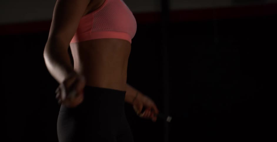 A woman is jumping rope wearing a pink top