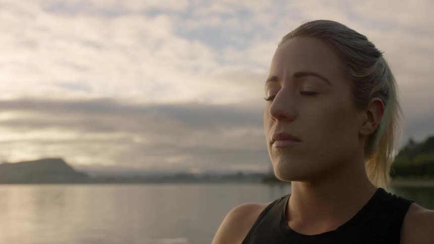 A woman is by the water with her eyes closed