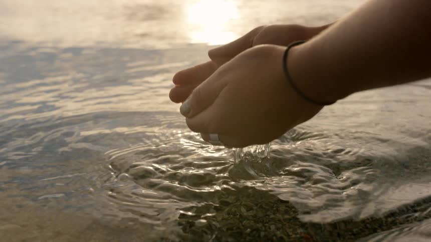 A woman scoops up water with her hands