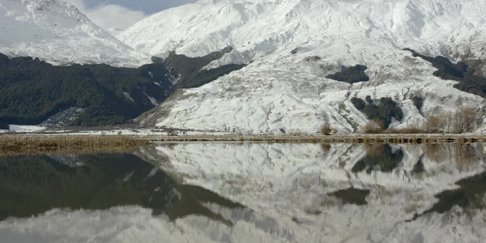 Snowy mountains surround a reflective lake