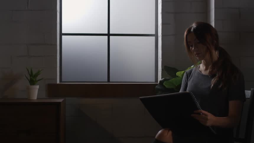 A woman is reading something in a dark room