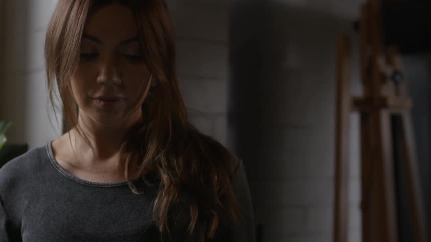 A woman looks down in a dark room