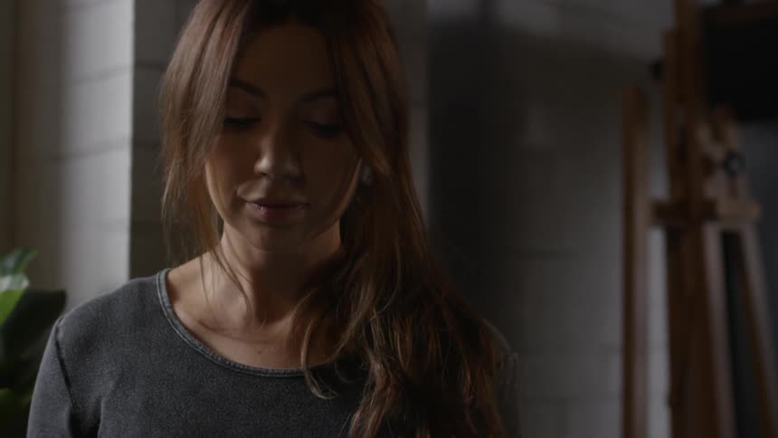 A woman looks downward while standing indoors