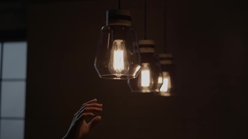 Three lights shining and go out as a hand reaches up to touch one