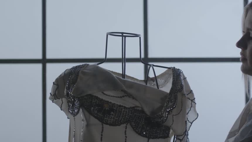 A woman puts a blouse on a wire mannequin