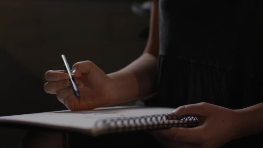 A person is writing in a notebook