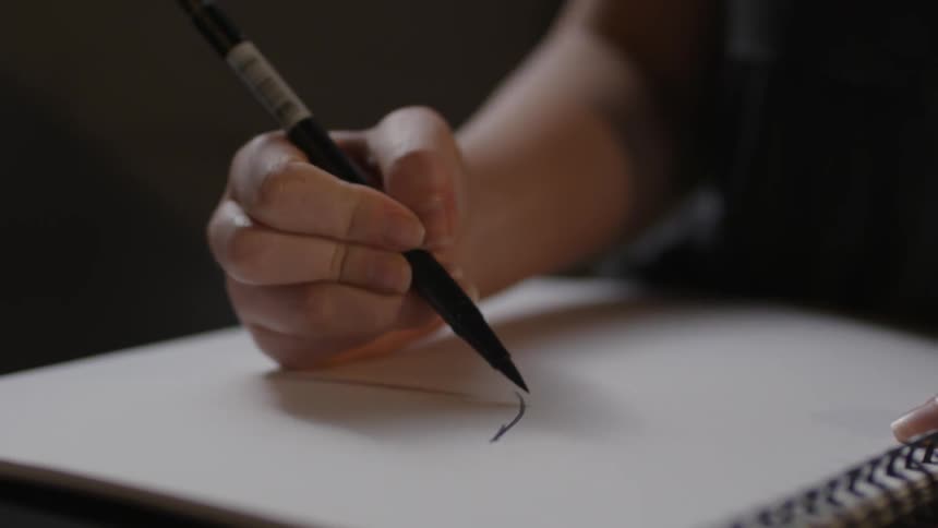 A woman draws in a notebook with a marker