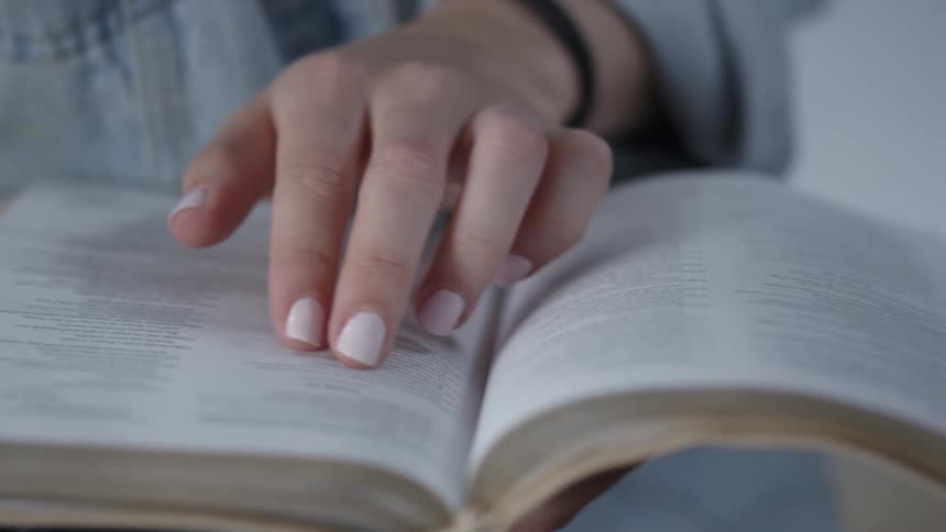 A woman reads a book following along with her fingers