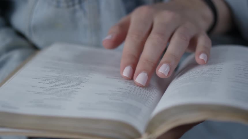 Woman reads a book following lines with her hand