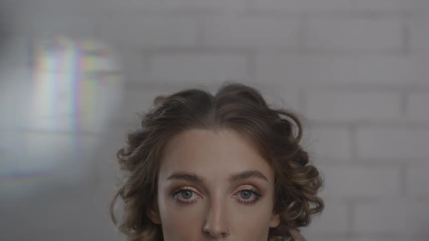 A woman with curly hair stares straight ahead