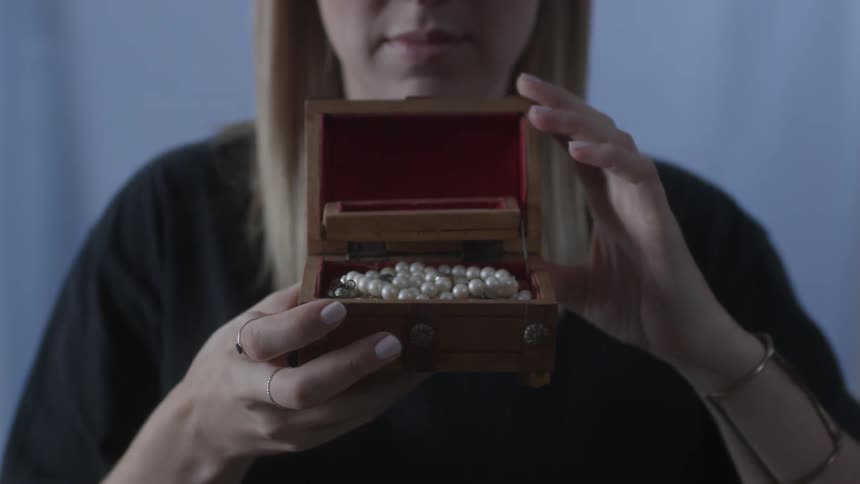 A woman opens a chest with pearls inside