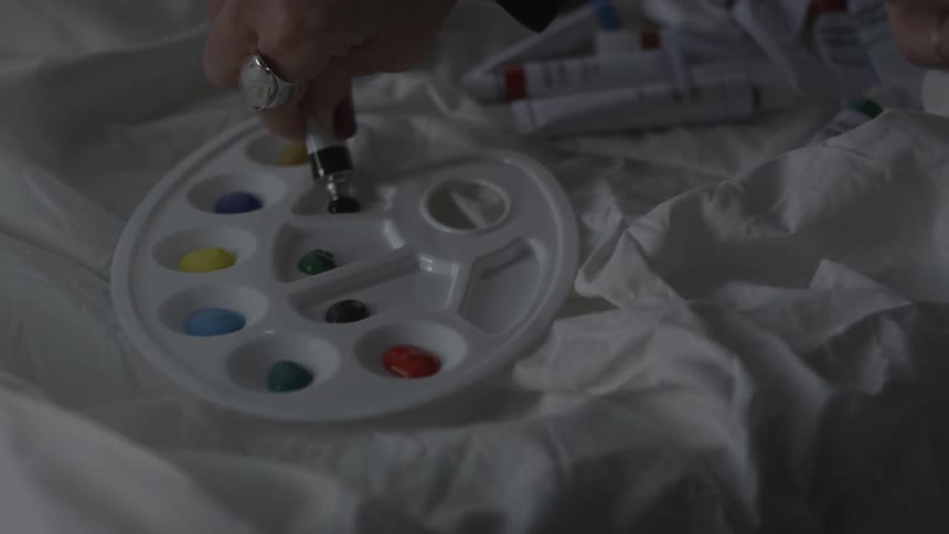 Black paint is squeezed into a palette