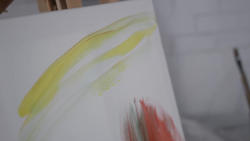 Person brushing yellow paint onto a canvas