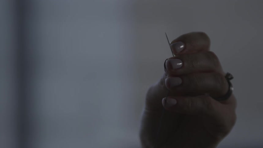 Hand holds a sewing needle