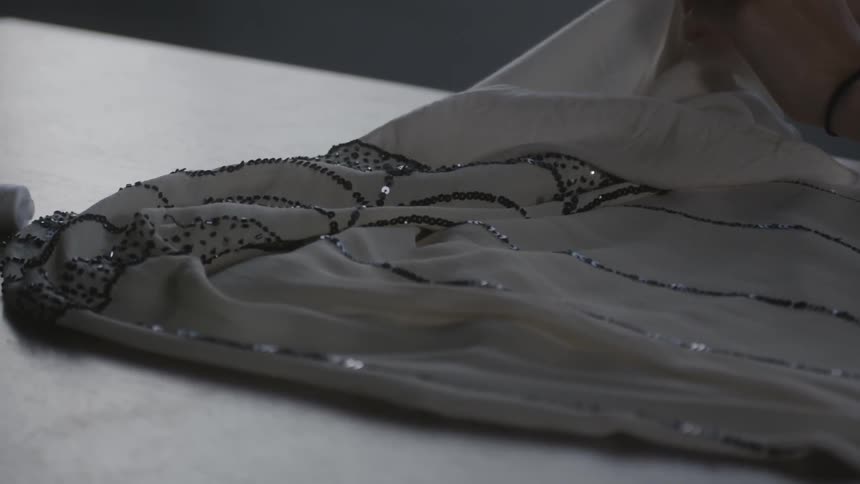 Woman examines a sequin covered dress on a table