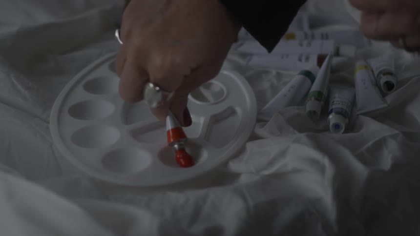 A person squeezes paint on a pan