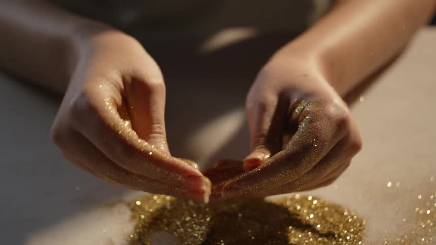 A woman rubs gold glitter on her hands