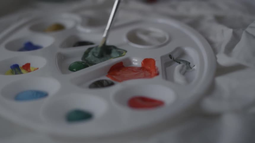 Paint brush mixes white and green paint