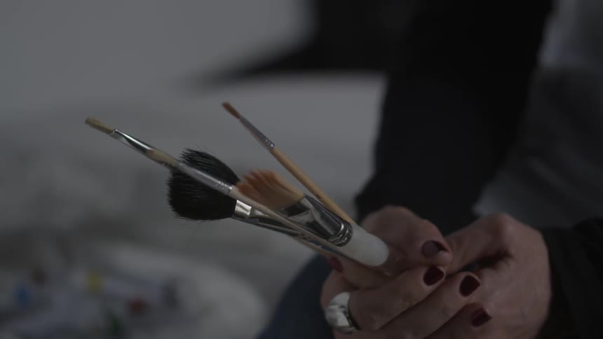 Person holds various sizes of paint brushes