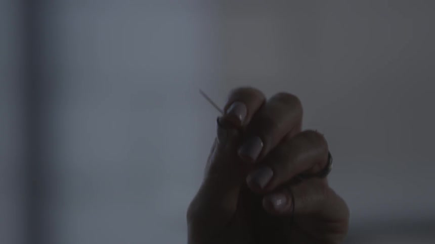 A woman holds a needle up
