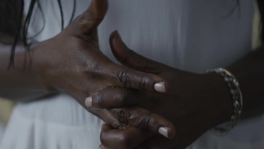 Person standing and clasping hands
