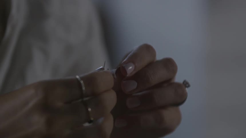 A woman pulls some thread and puts it on a needle
