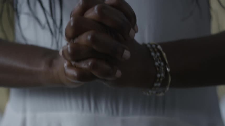 A woman tightly clenches her hands in front of her