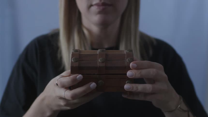 A woman is holding a small wooden chest