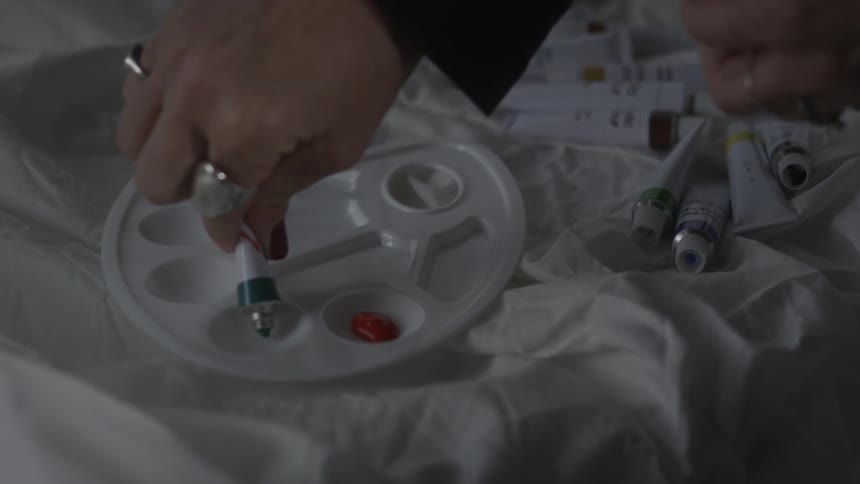 A person is preparing to paint squeezing paint out