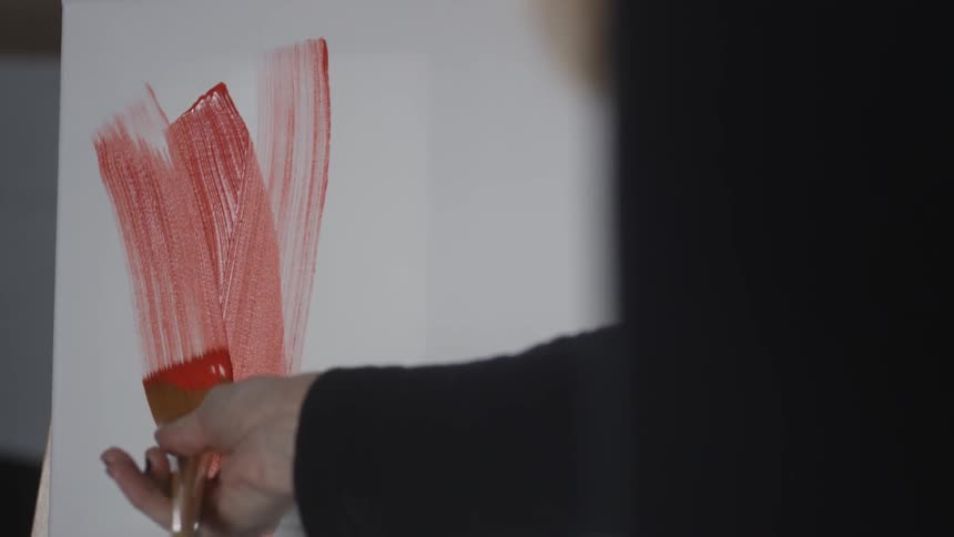 Person smears red paint onto a canvas