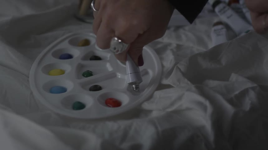 Person squeezes white paint into a small palette