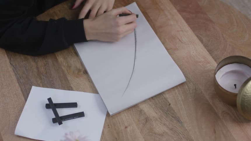 A person is drawing a picture on white paper