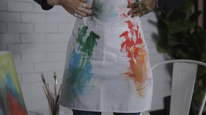 A woman wipes paint on her apron