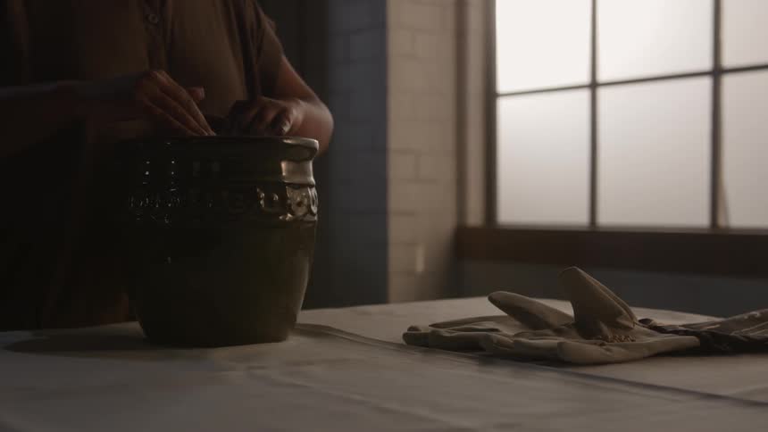 A woman digs in a pot of soil