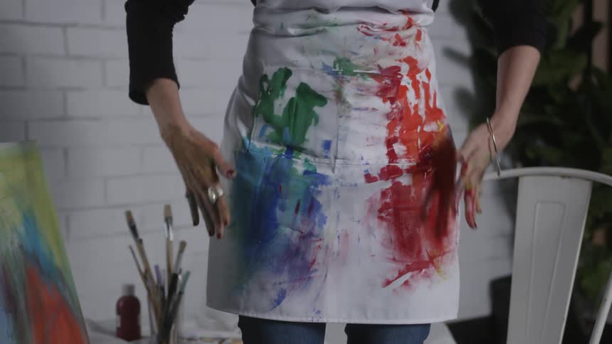 A woman tries to wipe the paint off her hands