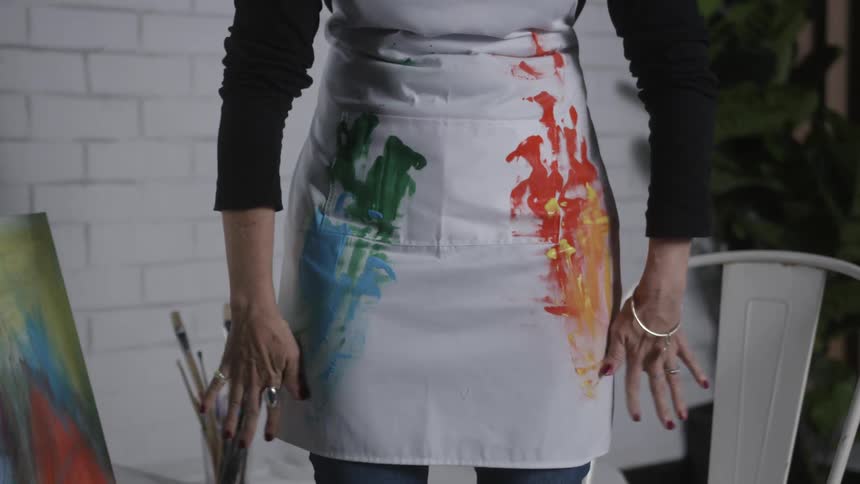 An artist wipes paint on her apron