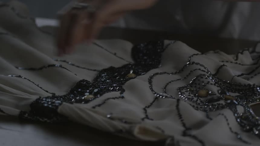 Person touches a sequined dress on a table