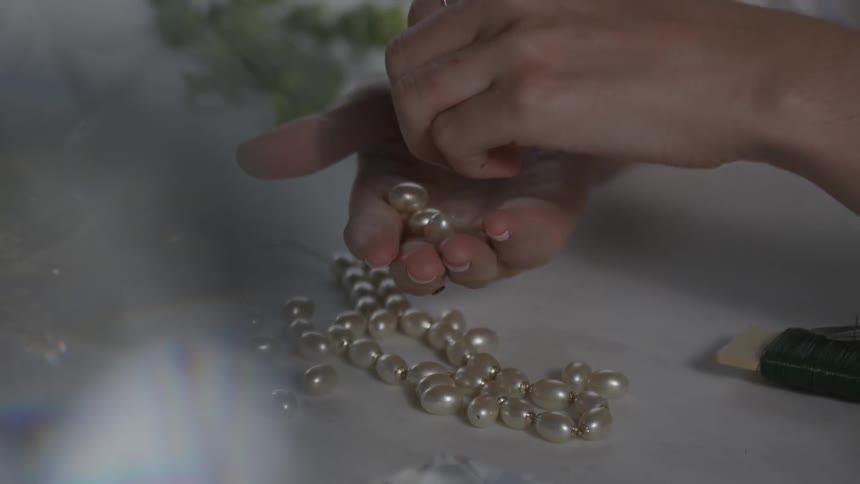A person is examining beads in her hands
