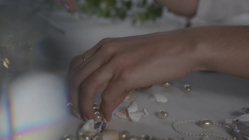 A person is picking up pearls on the table