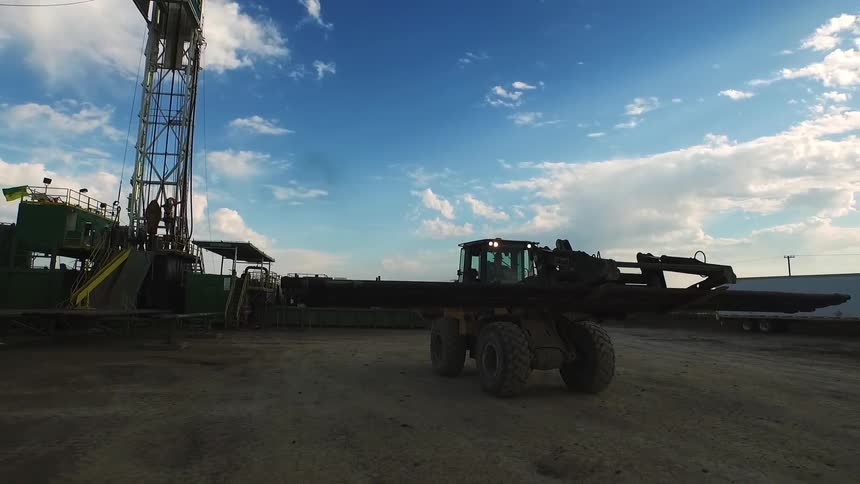 A bulldozer carries a beam on a work site