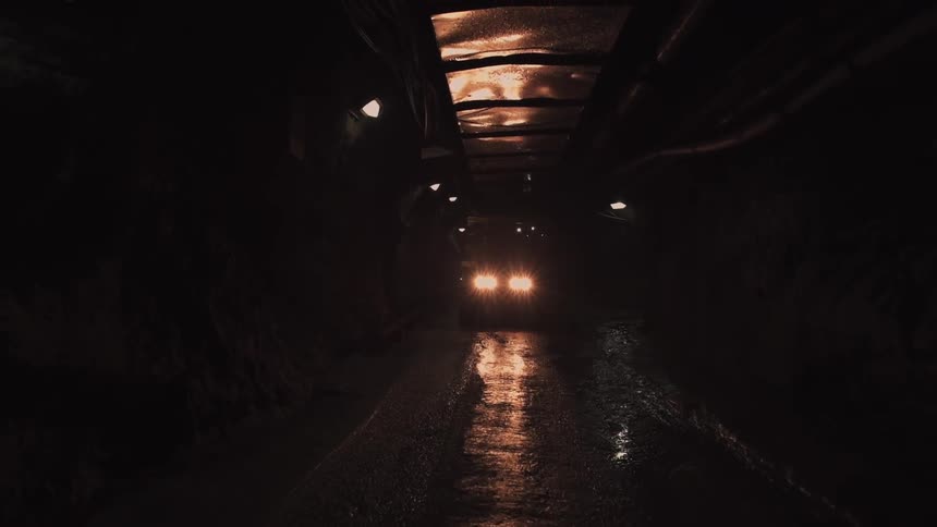 A vehicle drives down a dark tunnel