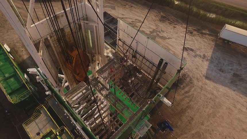 A worker stands on a large piece of machinery