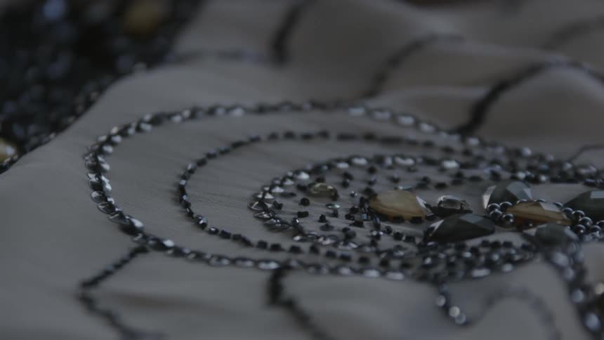 A person works on a garment embellished with stones and sequins