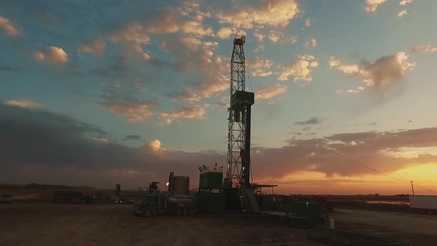 The sun is setting behind a large tower on a work site