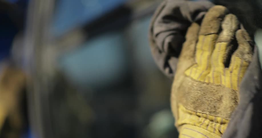 A gloved hand cleans a metal surface