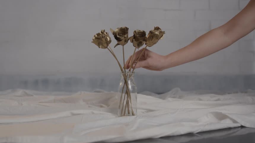 A small vase is being filled with golden roses