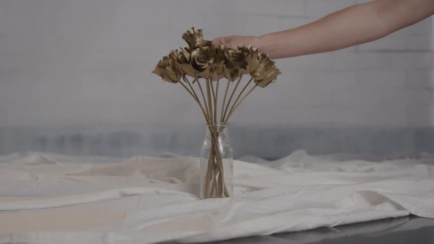 The vase is being filled with gold roses