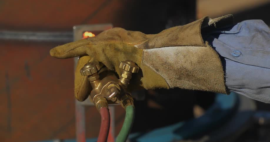 Gloved hands adjust a hose as water sprays out
