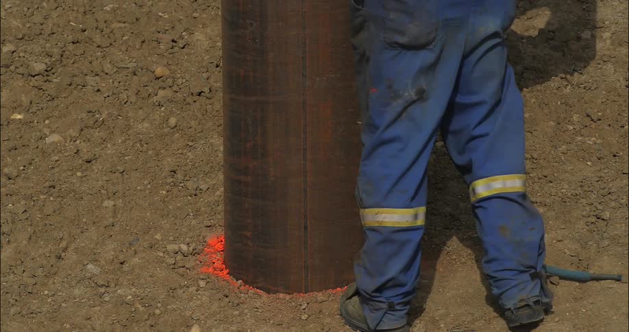 A person walks over to a metal pole in the dirt